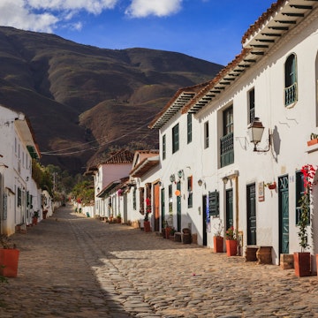 Villa de Leyva, Colombia - September 14, 2014: It is Sunday morning in Villa de Leyva and Calle or Street 14 is almost lifeless. The shops and restaurants will open; but, only towards noon. Founded in 1572 and located at just over 7000 feet above sea level on the Andes Mountains, Villa de Leyva was declared a National Monument in 1954 to protect it's colonial architecture and heritage. It is located in the Department of Boyaca, in the South American country of Colombia. In the background are the always present Andes Mountains. Photo shot in the morning sunlight; horizontal format. Copy space.